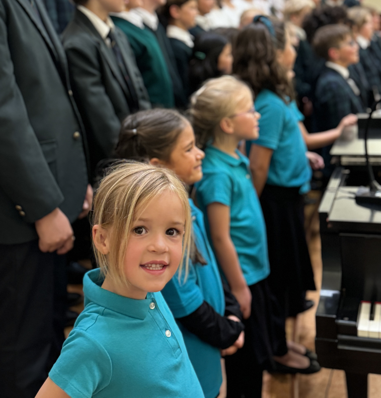 Smiling 8 year-old girl performing in large choir of mixed ages of boys and girls